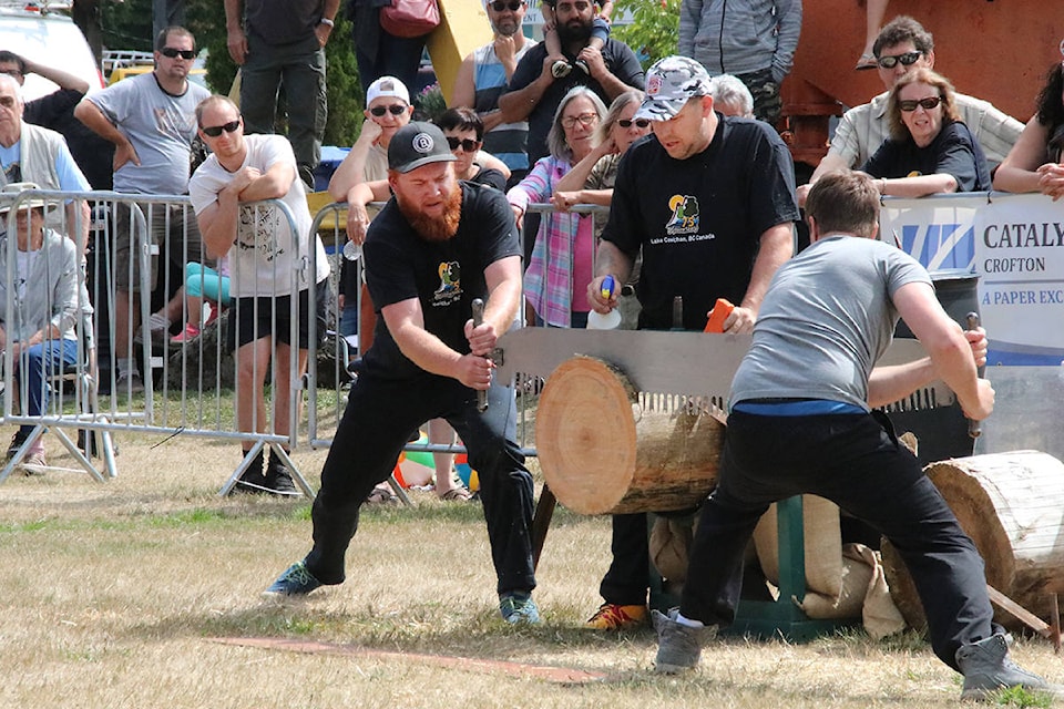 Sweating in the hot sun, competitors gut it out during the two-man saw crosscut saw event. (Lexi Bainas/Gazette)