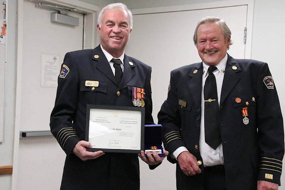 Bill Robertson, right, presents his 40-year ribbon and bar to Lake Cowichan Fire Chief Doug Knott on Nov. 4, 2019. (Lexi Bainas/Gazette)