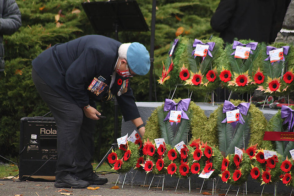 An organizer of the event makes sure the wreaths are lined up just so at the cenotaph at Lake Cowichan for the Remembrance Day ceremony in 2020. (Andrea Rondeau/Gazette)