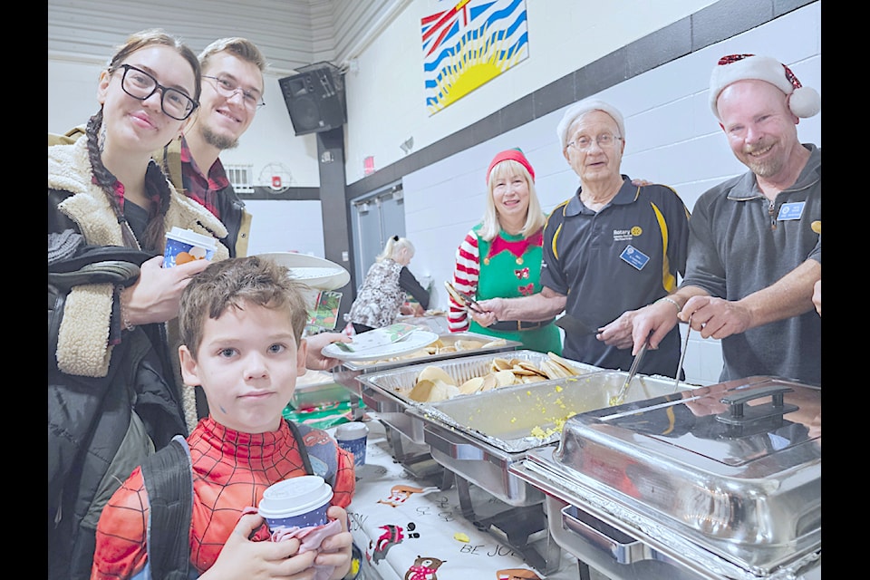 Student Tymur Milivkova, 7, with parents Daria and Val, were among more than 300 adults and kids who turned out for the annual Rotary Santa breakfast at Douglas Park Elementary School.