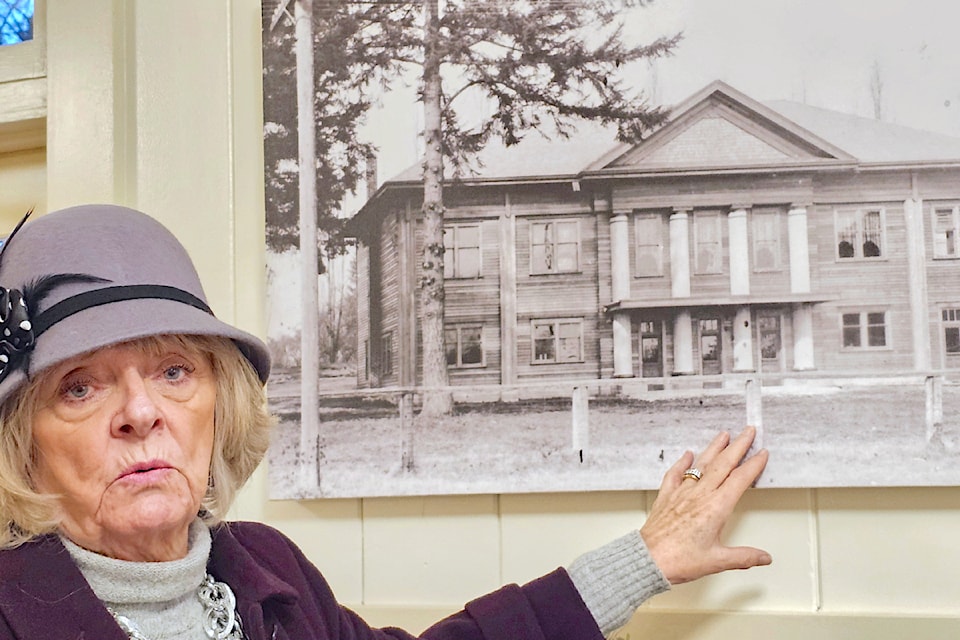 Sandy Cameron, current president of the heritage hall in Fort 91ԭ, with a photo showing the building under construction 100 years ago.