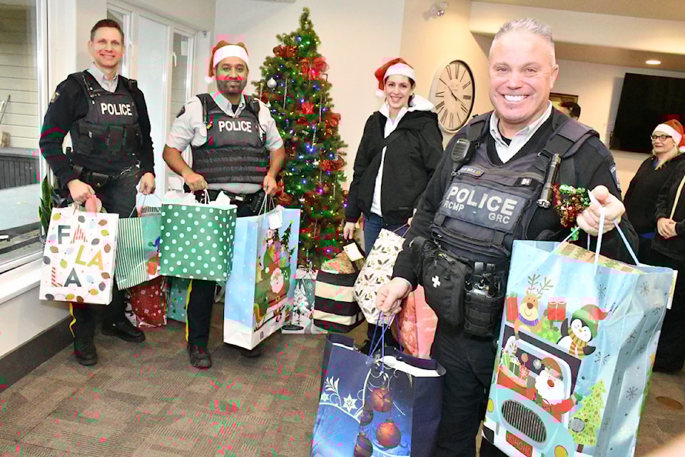 Const. Talbot McNutt (left), Const. Peter Mann, Township Councillor Barb Martens, and Const. Dennis Bell loaded up with packages to start delivering gifts Dec. 19, 2024. 