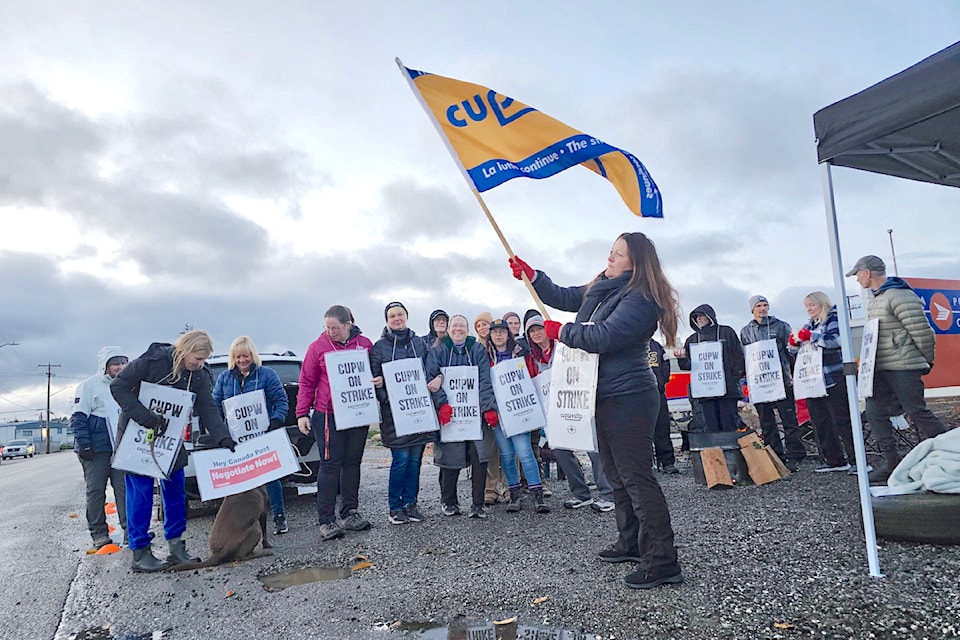 A postal worker waved a flag with a union logo during  picketing of the 91ԭ depot early Monday morning, Nov. 18. 