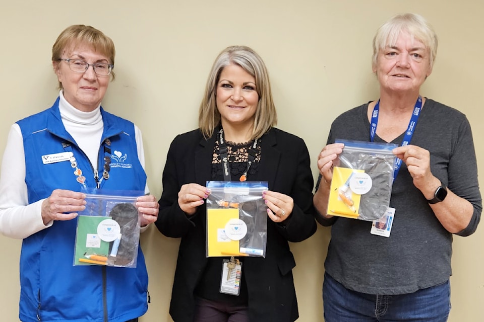 Board member Linda Claxton, manager of site services Julie Mick, and auxiliary past president Wanda Williams proudly display the new hallway kits made for hospital patients. 