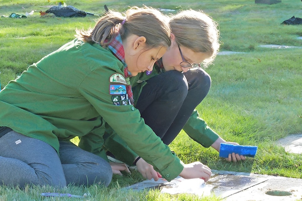 Using a toothbrush, water and patience, scouts Naomi Fandrich and Hannah Faulkner cleaned a veteran’s headstone in the Fort 91ԭ cemetery for a previous Nov. 11 service.