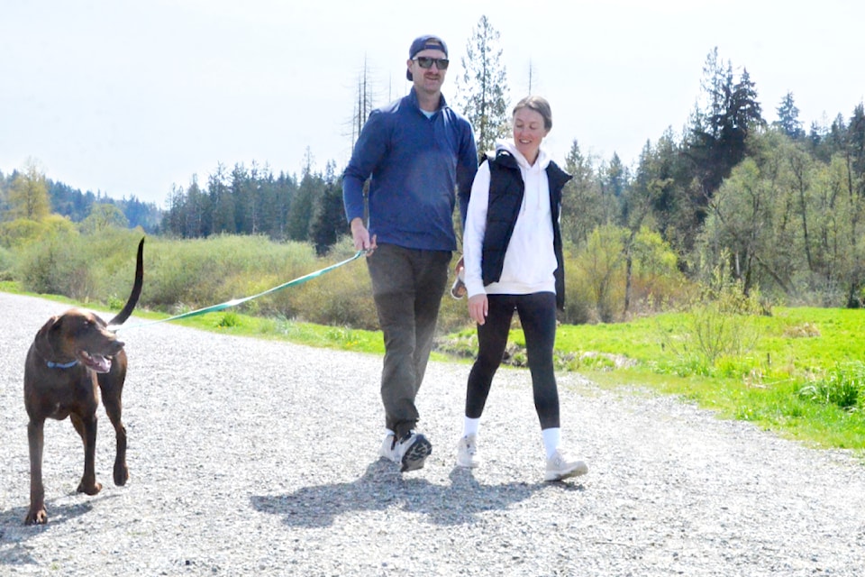 Mike Bosch and Nicole Jegodtka with their dog Miller on the dike at the edge of the new Nathan Creek Wetlands Park.