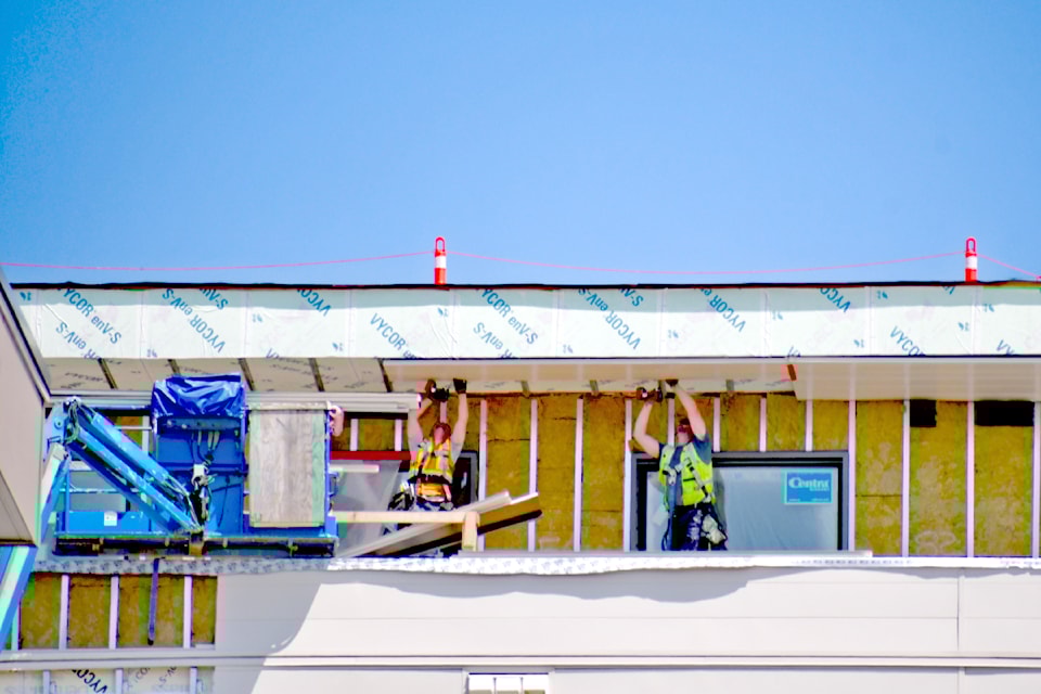 Workers ferried supplies up to the top floor of the Aldergrove Town Centre building with a crane as they worked on the exterior in June.