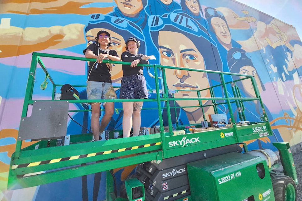 Taj Jamal (left) and Randi Hamel applied  finishing touches to a 30- by 80-foot mural at  Airport