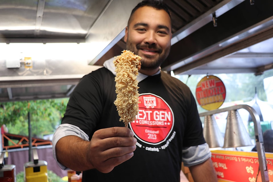 Jason Faria from Corn Dog King with a fresh ramen corndog: a hot dog layered with mozzarella cheese, batter and crumbled ramen noodles. (Baneet Braich/Black Press Media)