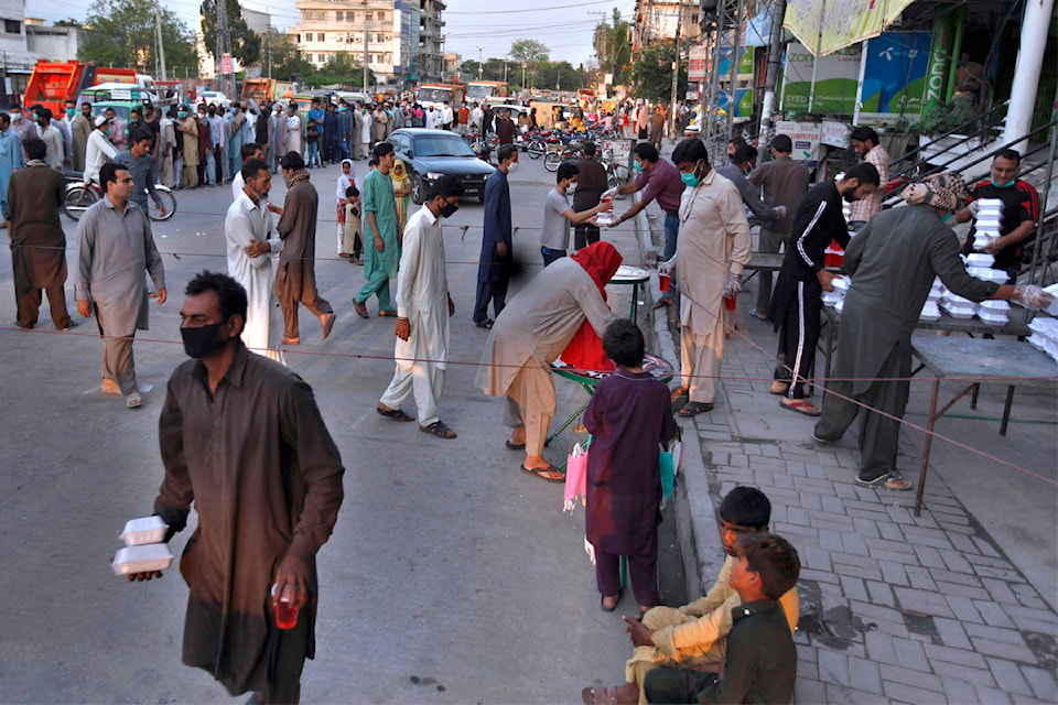 People receive food boxes and a traditional sweet drink distributed by volunteers for breaking their fast, in Rawalpindi, Pakistan, on May 3. Photo: AP Photo/Anjum Naveed