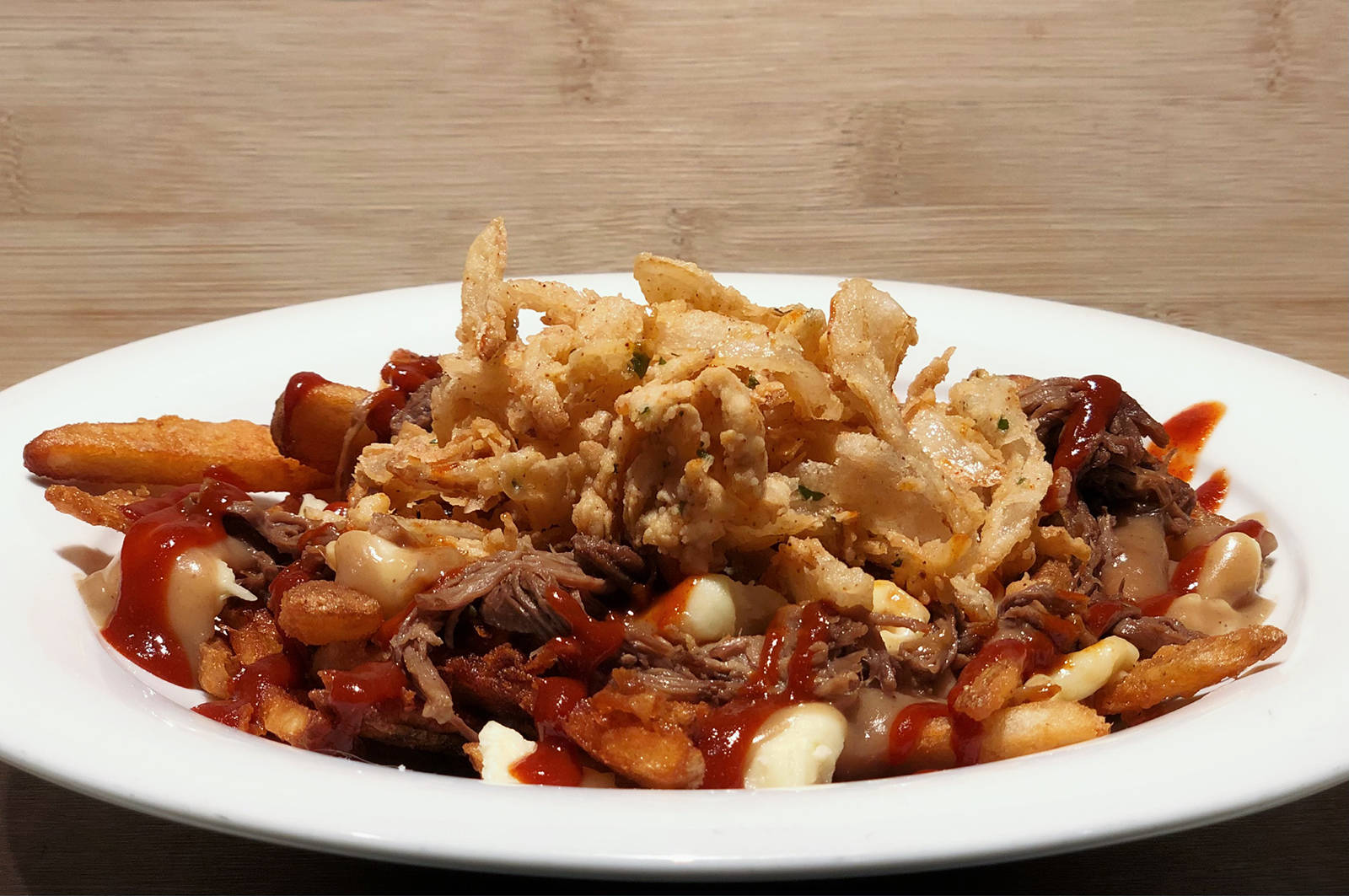 Darcy聮s Pub Westshore offers its BBQ Brisket Poutine 鈥 crispy beer battered fries, real cheese curds, house-made brisket gravy, and 12-hour braised shredded beef brisket, topped with a spicy barbecue drizzle and fried buttermilk onions.