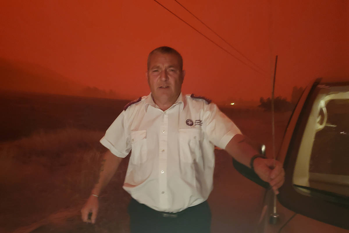 Trevor White, operations manager for the Abbotsford-based company Hospital Transfers, stands outside in the Okanagan while the sky turned red in the middle of the day due to wildfires, on Aug. 16, 2021. (Submitted)
