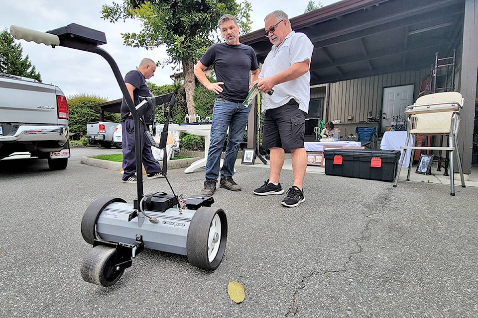A seller demonstrated a remote-controlled golf bag carrier to a prospective buyer. More than 500 bargain hunters are estimated to have taken part in the third annual giant Aldergrove garage sale held on Saturday, Aug. 22. (Dan Ferguson/Langley Advance Times)
