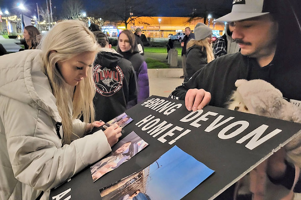 Nikki Goodrick, signed a missing poster of her brother Devon at a Tuesday, Nov. 16 vigil in Langley City’s Douglas Park. (Dan Ferguson/Langley Advance Times)