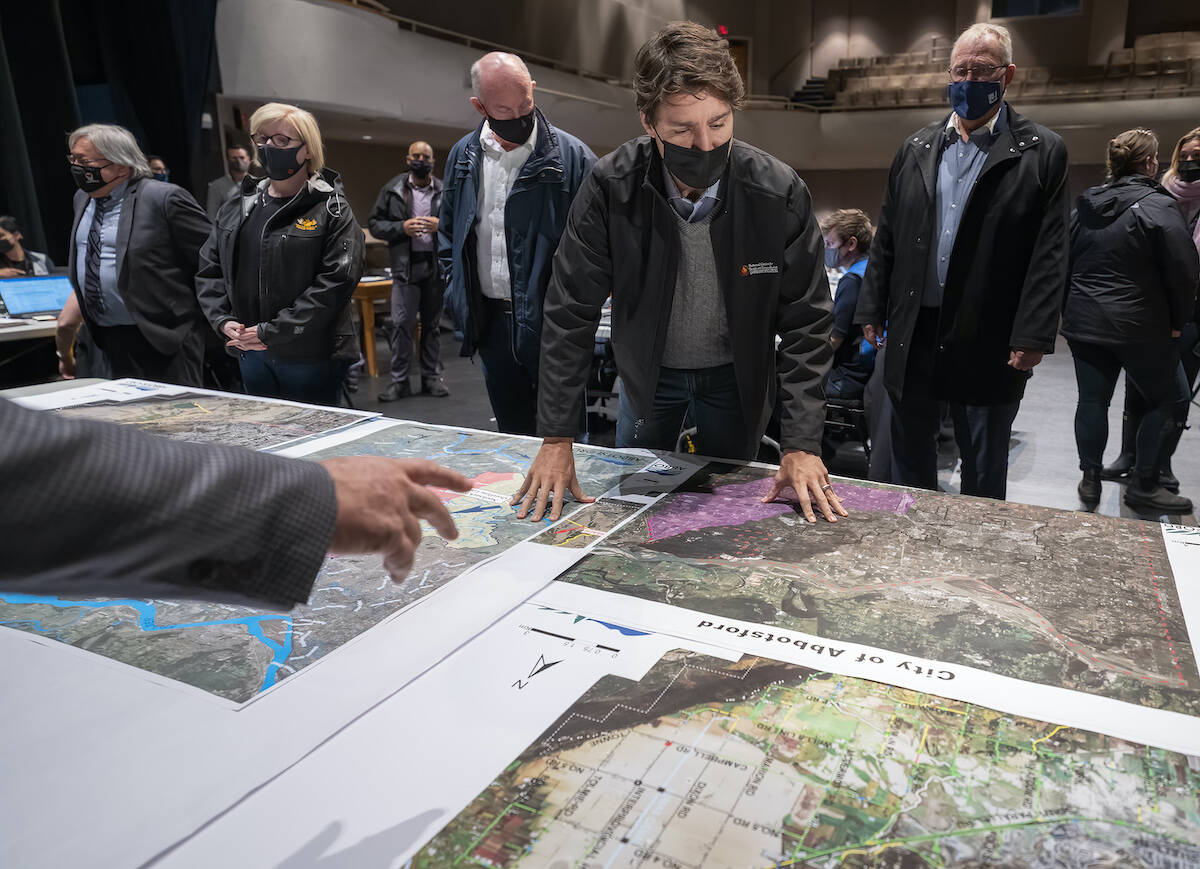 Prime Minister Justin Trudeau looks over maps as he surveys the damage left behind from the flood waters in Abbotsford, B.C., Friday, November 26, 2021. THE CANADIAN PRESS/Jonathan Hayward