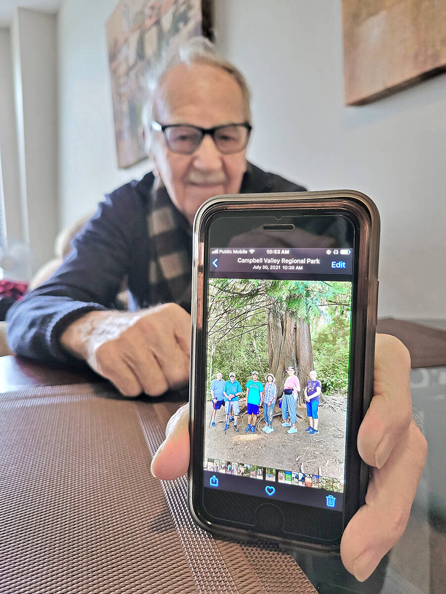 Dale Attrell shows off a photo of a summer walk in Langley. On the morning of a walk, he checks the conditions, then sends a text to all participants. (Dan Ferguson/Langley Advance Times)