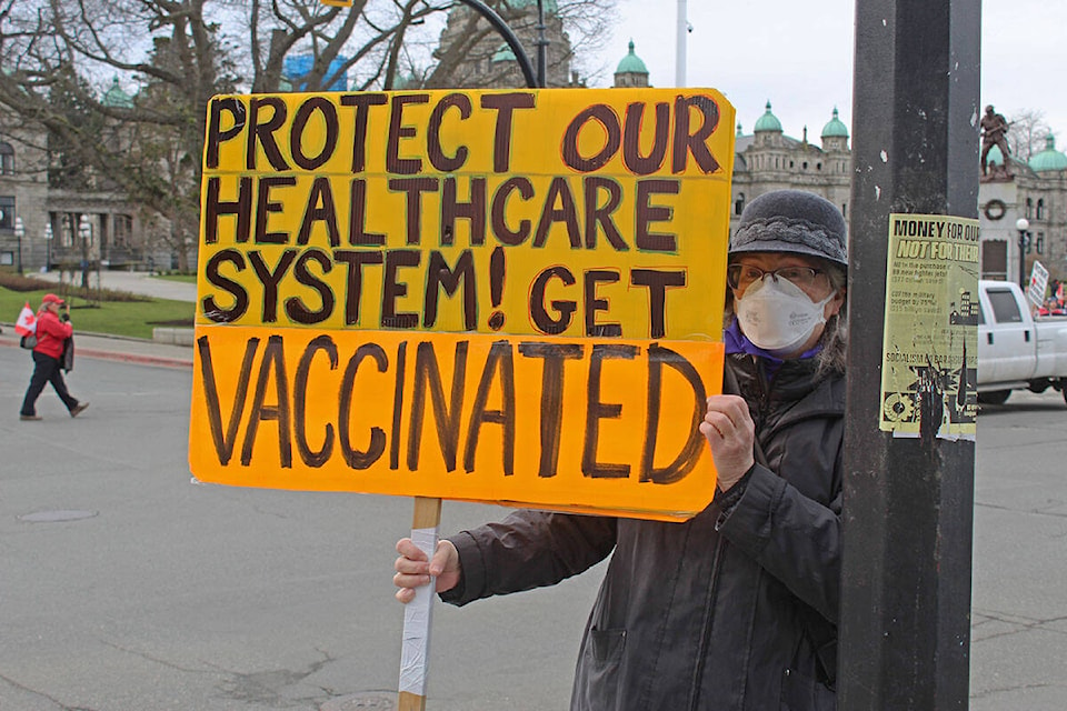 Freya Keddie holds a sign at the B.C. legislature to show her support for vaccination, amidst demonstrators against mandates. (Megan Atkins-Baker/News Staff)