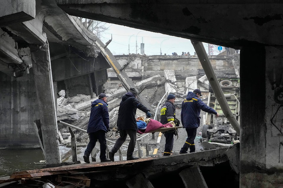 Ukrainian rescue workers carry an elderly woman under a destroyed bridge in Irpin, close to Kyiv, Ukraine, Friday, April 1, 2022. Talks to stop the fighting in Ukraine resumed Friday, as another attempt to rescue civilians from the shattered and encircled city of Mariupol broke down and Russia accused the Ukrainians of a cross-border helicopter attack on an oil depot. (AP Photo/Efrem Lukatsky)