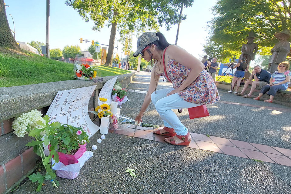 A woman laid a wreath of flowers at a Tuesday night (July 26) vigil for the victims of the Langley shootings at Innes Corners Plaza in Langley City. She was one of around 100 people who attended. (Dan Ferguson/Langley Advance Times)