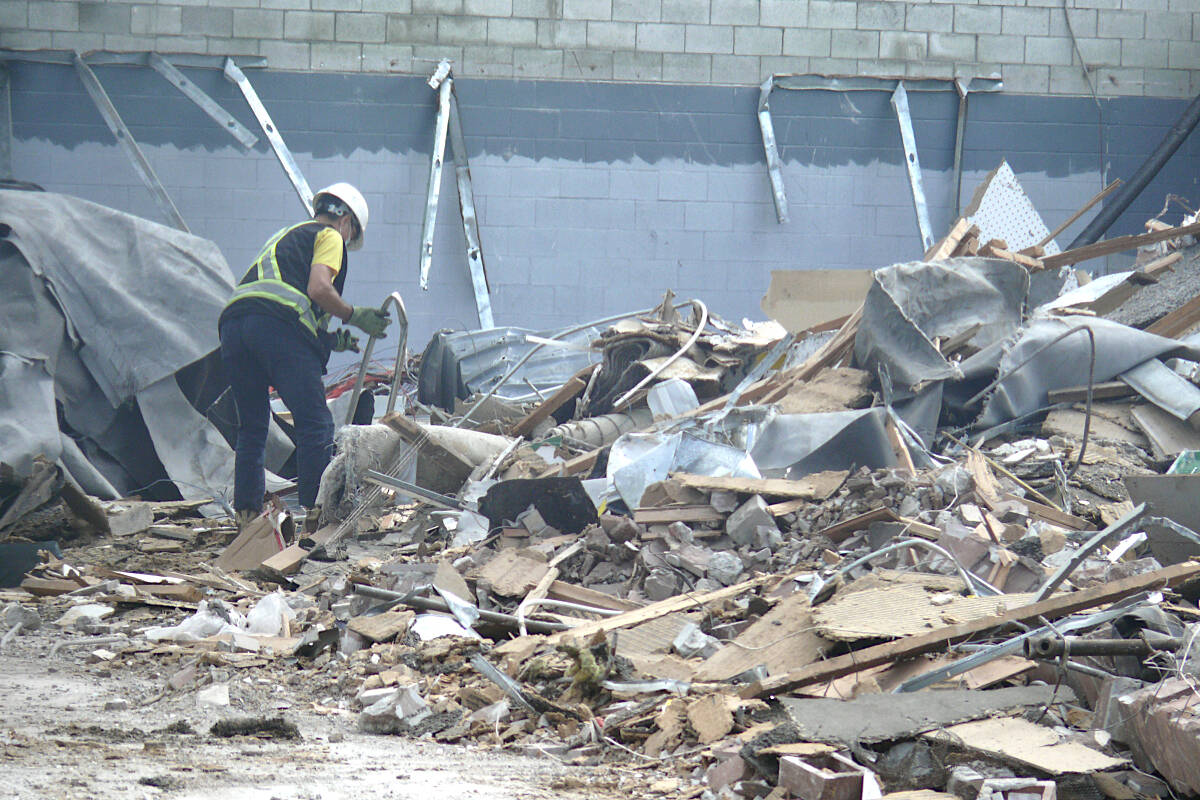 A demolition crew members examines debris at the former Aldergrove Mall on Saturday, Aug. 18, where two excavators were clearing the way for a new development. (Dan Ferguson/91原创 Advance Times)