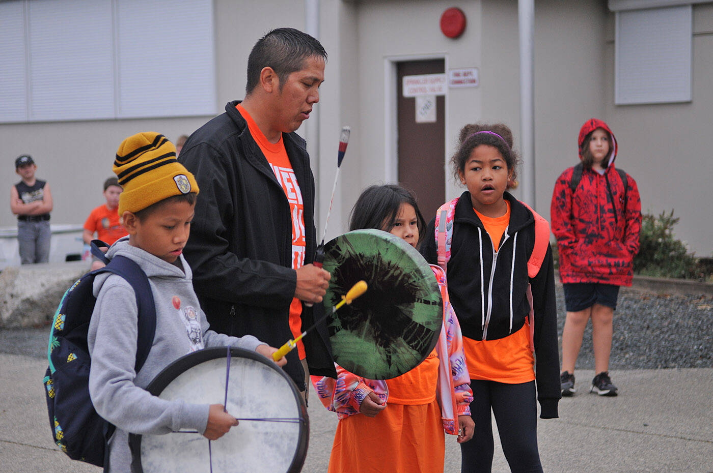 Justin Williams drums and sings with children outside Bernard Elementary on Thursday, Sept. 29, 2022. The drumming and singing happened as children arrived that morning, just before the whole school gathered for a group photo with their new orange T-shirts given to by the parent advisory council. (Jenna Hauck/ Chilliwack Progress)