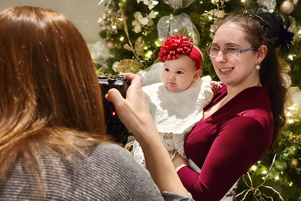 Hayley Clay, with 6-month-old Juniper, posed for pictures at the Christmas Tea hosted by The Thank You For Caring Society. The event drew 350 people to the Cascades Casino Ballroom Sunday afternoon, Nov. 20. (Dan Ferguson/Langley Advance Times)