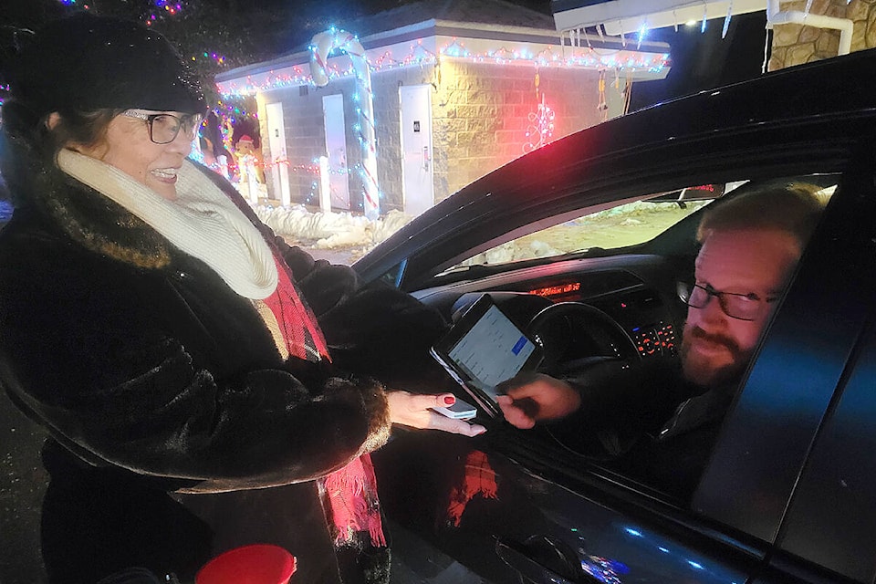 Volunteer Vicki Asada used a card reader to accept one driver’s donation at the Williams Park Christmas lights display on Saturday, Dec. 3. Money donated goes to purchase more lights by the non-profit volunteer society that stages the annual event. (Dan Ferguson/Langley Advance Times.
