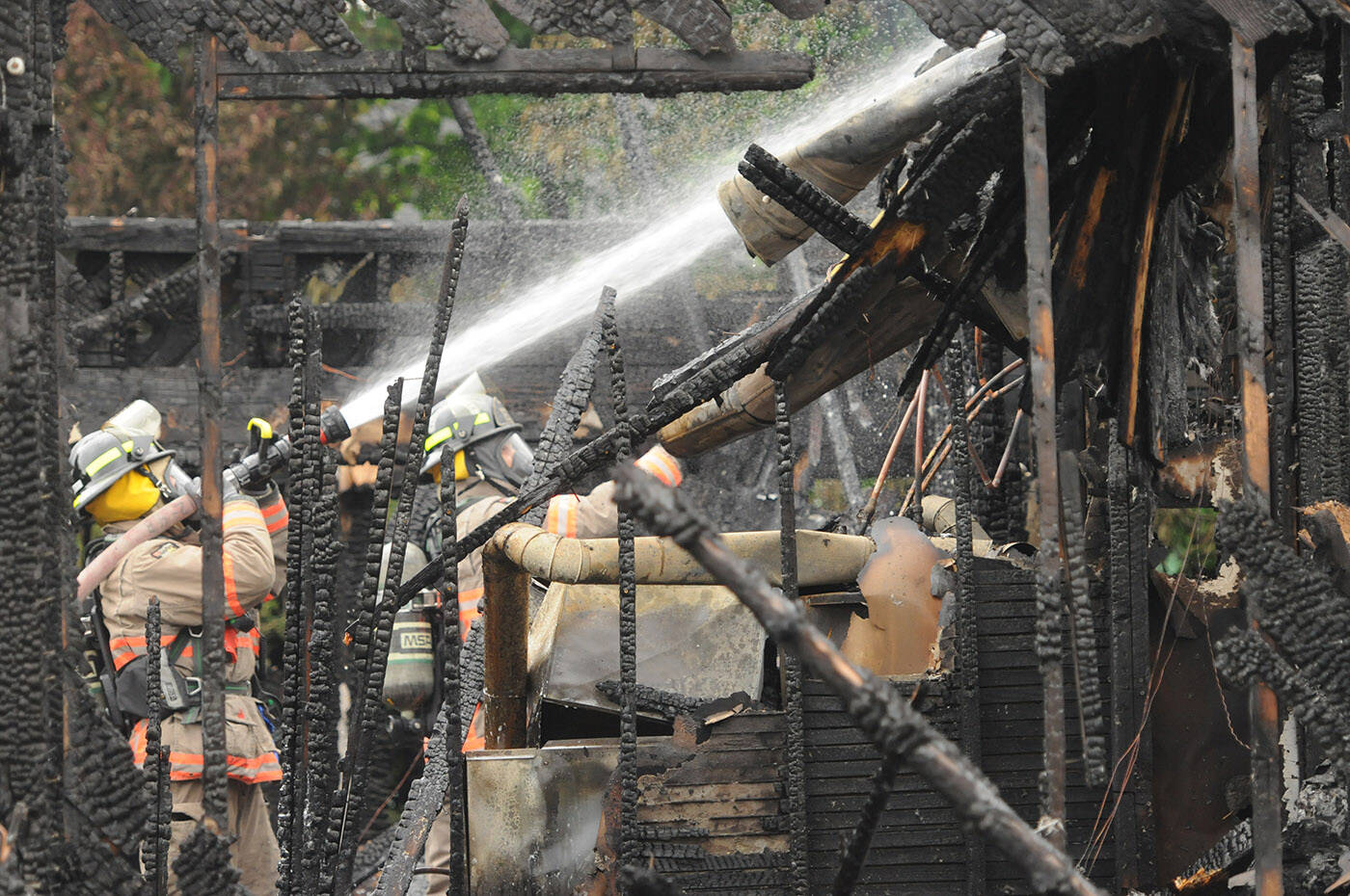 Crews with the Chilliwack Fire Department douse hot spots hours after this house at Knight Road and Queen Street burned to the ground on Tuesday, May 23, 2023. (Jenna Hauck/ Chilliwack Progress)