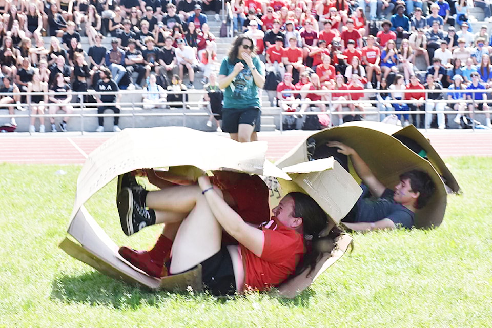 Grade 11 student, Siobhan Cocking, left, and Grade 10 student Jackson McKay, race in a box relay under supervision by teacher Gillian Hampton, during Spirit Fest at Maple Ridge Secondary. 