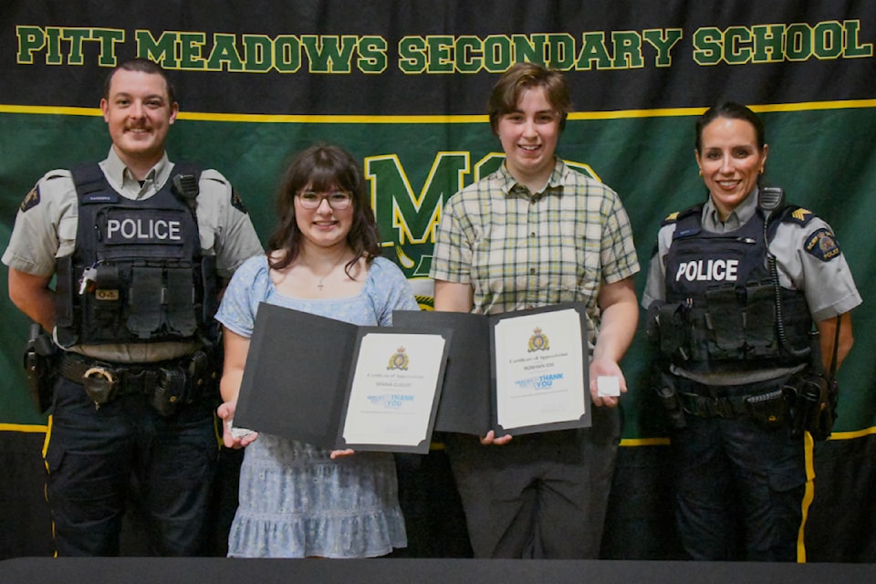 Ridge Meadows RCMP recognized Pitt Meadows Secondary students Sienna Gubert (second from left) and Siobhan Job with coins, which were presented by Const. Michael Sanders (left) and Staff Sgt. Michelle Luca (right).