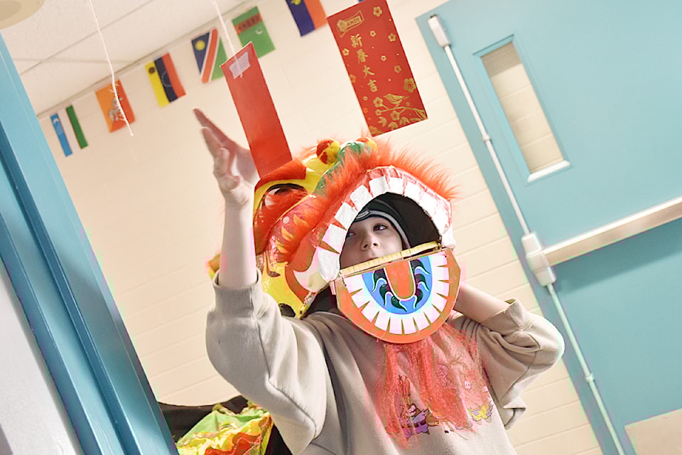 Grade 4 student Munro Metcalfe takes a red envelope in a doorway at Albion Elementary during a lion dance parade to celebrate the Lunar New Year. 