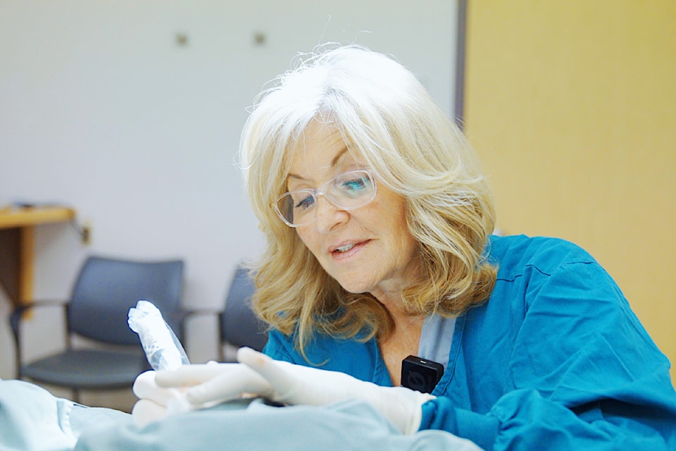 Sandi Saunier, a surgical nurse at Eagle Ridge Hospital, works on Malcolm Matheson's tattoo.
