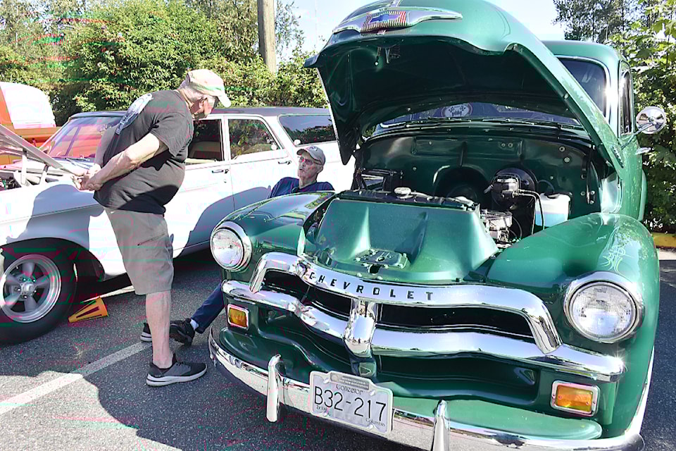 Ed Swanson, seated, owner of a 1955 first series Chevy pickup, talks with a guest at the car show.