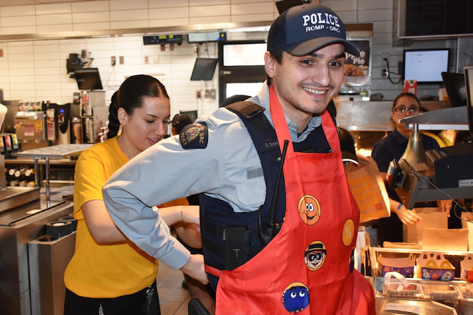 Ridge Meadows RCMP officer gets help putting on his McHappy Day apron.