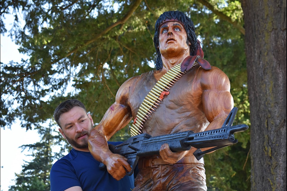 Carver Ryan Villiers puts finishing touches on the lifelike chainsaw carving of John J. Rambo (played by Sylvester Stallone) before it was installed at Hope’s Memorial Park Aug. 14, 2020. (Emelie Peacock/Hope Standard)
