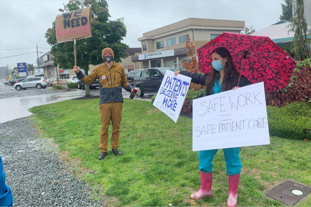 Chilliwack General Hospital emergency room physician Dr. Marc Greidanus (left) with a sign that says We Need Nurses on the front and STAT on the back, at a rally to support nurses in front of Chilliwack MLA Dan Coulters constituency office on Sept. 17, 2021. (Margaret Reid photo)