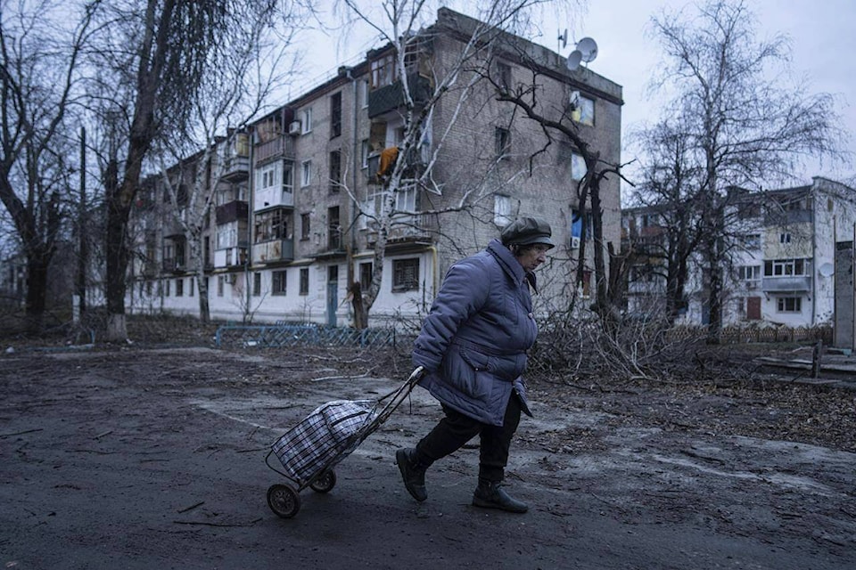 A local woman walks to the distribution point of humanitarian aid in front of housing which was damaged by Russian shelling in Kupiansk, Kharkiv region, Ukraine, Wednesday, Dec. 28, 2022. (AP Photo/Evgeniy Maloletka)