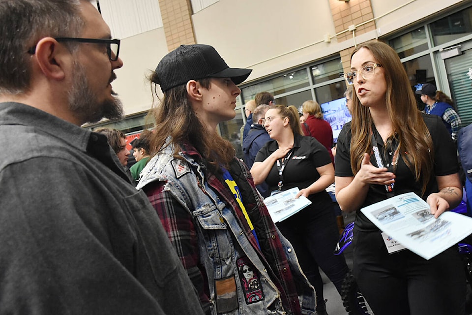 Krysta Taylor, parts and accessories manager with GA Checkpoint Motorsports, right, talks with Brady Yardley, 16, a Grade 11 student at Samuel Robertson Technical, who was at the trades show with his father Curtis Yardley. (Colleen Flanagan/The News)