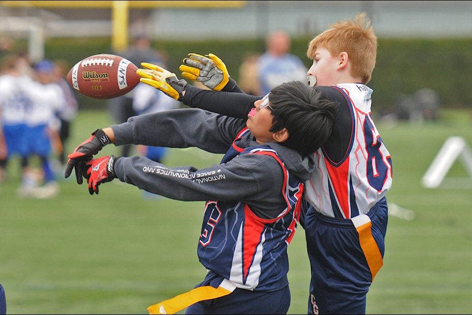 Hadi Sajid (blue jersey) of Team Larricq and Gage McStravick (white) of Team Clark – both with Chilliwack Giants Minor Football Association – jump to catch the ball during a U-12 game at a flag football jamboree at Townsend Park on Saturday, April 22, 2023. (Jenna Hauck/ Chilliwack Progress)
