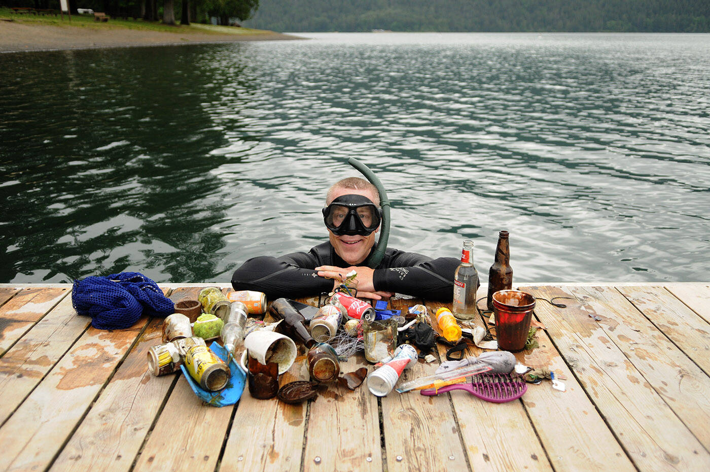 Steve Clegg poses by some of the items he found at the bottom of Cultus Lake on Friday, June 16, 2023. (Jenna Hauck/ Chilliwack Progress)