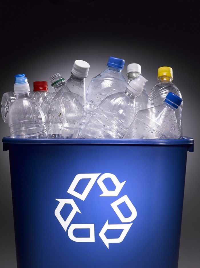 Plastic bottles in trash bin with recycle sign