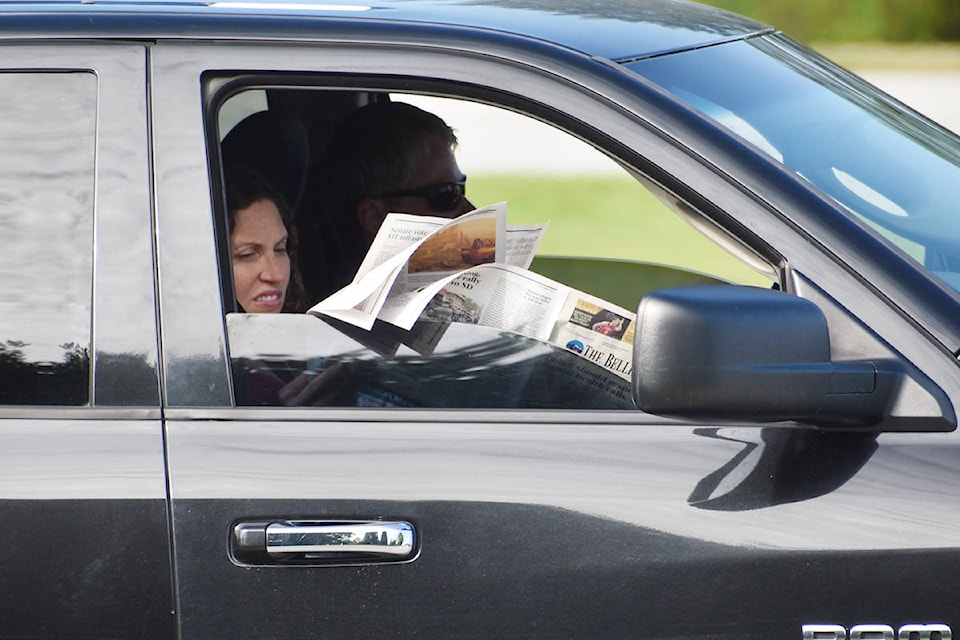 A woman reads a newspaper while waiting in line at the Peace Arch border crossing Monday. (Aaron Hinks photo)