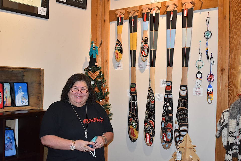 I-Hos Gallery manager Ramona Johnson shows some of the paddles available at the retail outlet. Photo by Terry Farrell