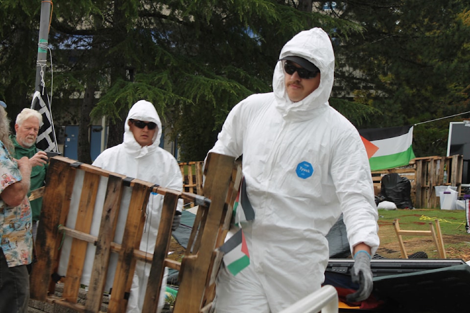 Workers dismantle the encampment structures within minutes of the court deadline on Sunday, Aug. 18.