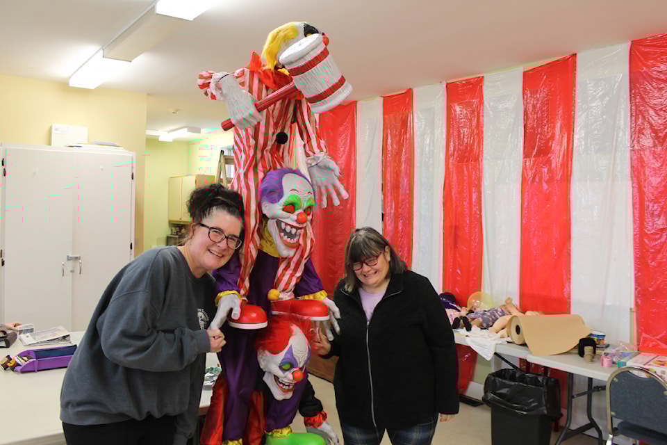 Jennifer Fowler, executive director of the Clay Tree Society, along with a client, work on setting up their haunted house's creepy circus room. 