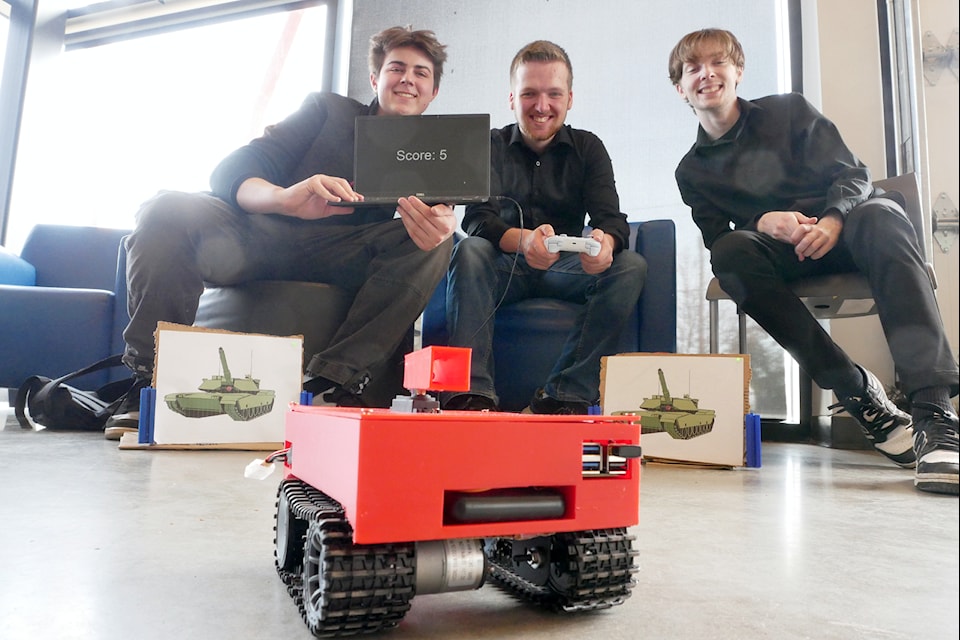 Gavin Lane, left, Zack Jenkins and Dylan Michalopoulos demonstrate the Pyro Tank, a prototype for a remote-control laser tag tanks game where multiple players driving multiple tanks can take out their opponents with well-aimed laser hits. (Chris Bush/News Bulletin)
