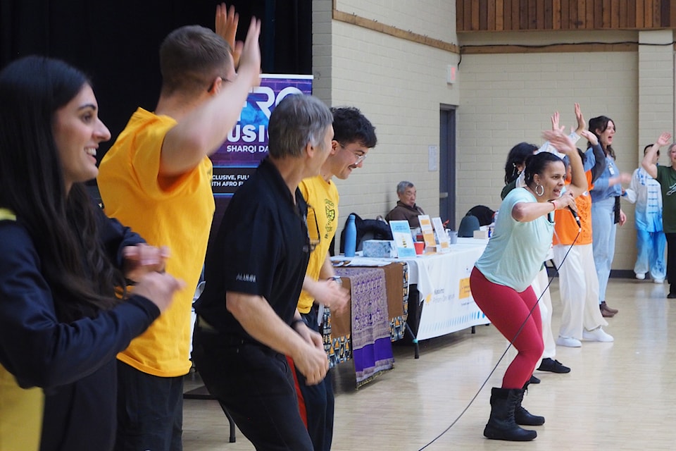 Dance teacher Tania Amaral, with microphone, of Afro Fusion Sharqi Dance, leads fair visitors and exhibitors through a series of African dance-style moves. 
(Chris Bush/News Bulletin)