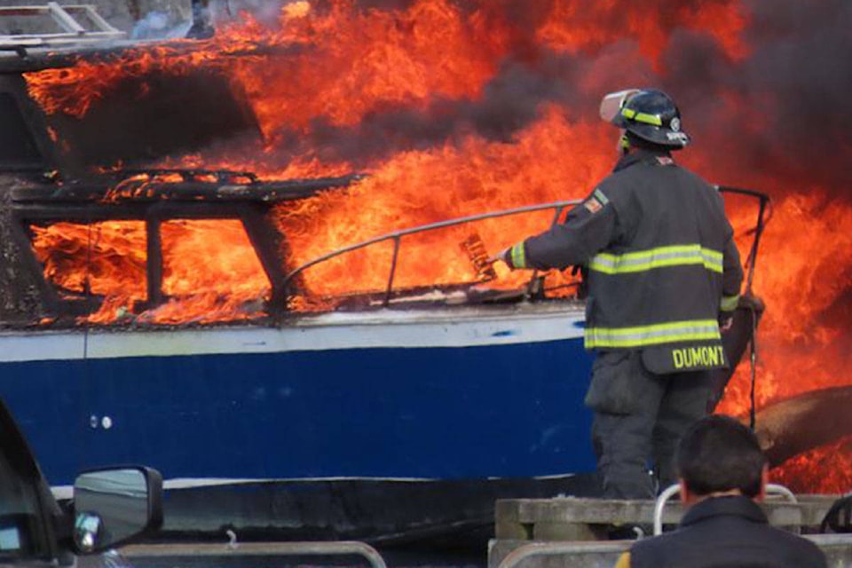 A firefighter works to extinguish one of the boats in Tuesday night’s fire. Photo supplied by NC via Facebook