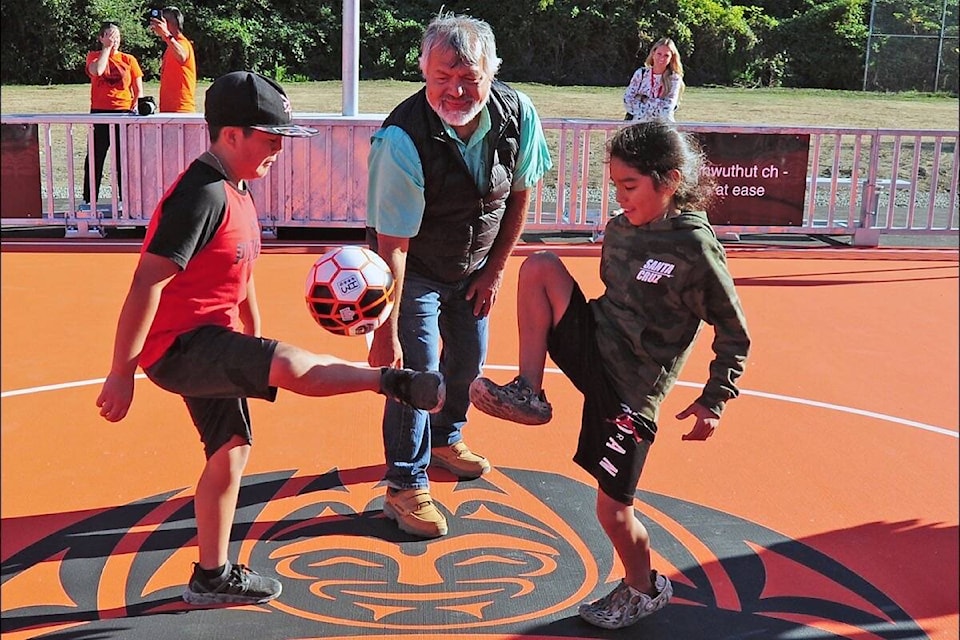 Snaw-Naw-As Chief Gordon Edwards tosses the ball to get the children to start playing on its new mini soccer pitch. (Michael Briones photo)