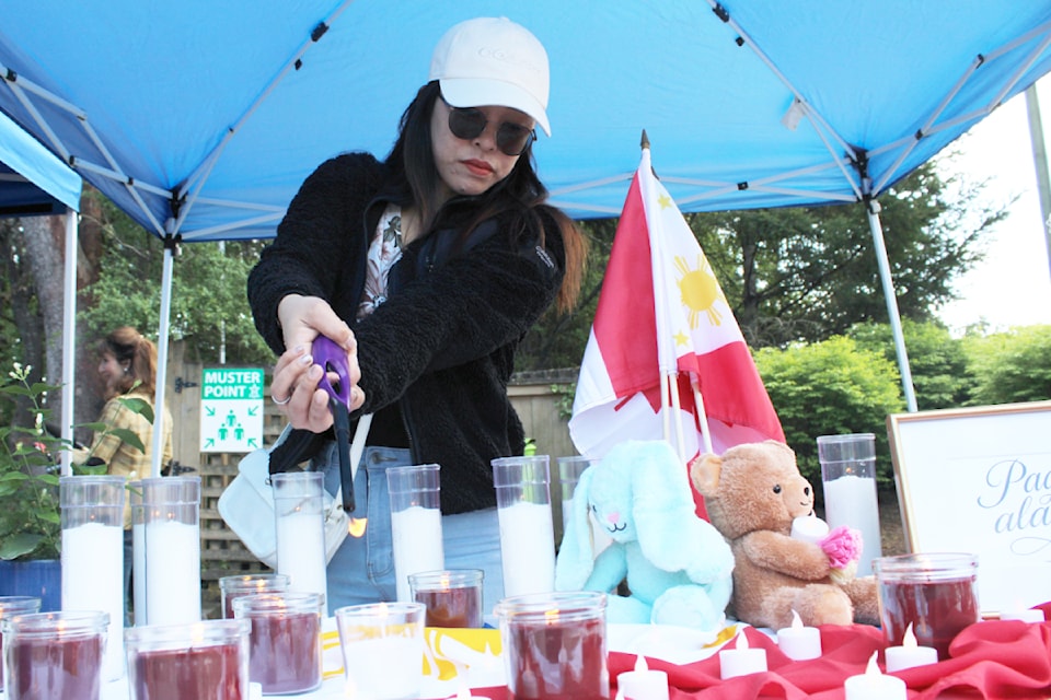 Jinky Dagcuta lights candles at a memorial table at a Lapu Lapu Festival tragedy vigil in Nanaimo. (Karl Yu/News Bulletin) 